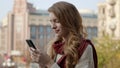 Beautiful woman typing sms by phone outdoors. Cute girl holding phone on street. Royalty Free Stock Photo