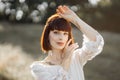 Indian american lady in white dress, with tattoos, boho feathers, posing to camera outdoor Royalty Free Stock Photo