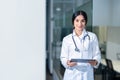 Portrait of beautiful Indian female doctor wearing white lab coat, using tablet computer Royalty Free Stock Photo