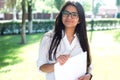 Portrait of a beautiful indian girl. Business woman in glasses holds business papers in hands in green park Royalty Free Stock Photo