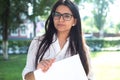 Portrait of a beautiful indian girl. Business woman in glasses holds business papers in hands in green park Royalty Free Stock Photo