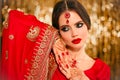 Portrait of beautiful indian girl in red bridal sari over golden bokeh. Young hindu woman model with kundan jewelry. Traditional Royalty Free Stock Photo