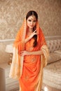 Portrait of beautiful indian girl in traditional saree in luxury interior. Young hindu woman model with kundan golden jewelry set