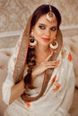 Portrait of beautiful indian girl in traditional saree in luxury interior. Young hindu woman model with kundan golden jewelry set Royalty Free Stock Photo