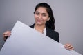 Portrait of a beautiful Indian young business woman in a business suit holding a gray blank paper in her hand, stocking. Free