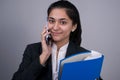 Portrait of a beautiful Indian young business woman in a business suit, holding in her hand a blue folder with documents, talking Royalty Free Stock Photo