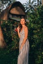 Portrait of beautiful lady in white striped dress with balinese vila background