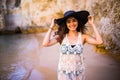 Portrait of beautiful latin girl on the beach with black hat smile neat ocean and rocks on summer vocation Royalty Free Stock Photo