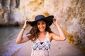 Portrait of beautiful latin girl on the beach with black hat smile neat ocean and rocks on summer vocation Royalty Free Stock Photo