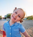 Portrait of a beautiful liitle girl in blue plaid summer dress with blonde hair close-up. Joyful cute child smiling Royalty Free Stock Photo