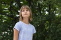 Portrait of a beautiful liitle girl close-up on a background of green leaves