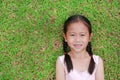 Portrait of beautiful little Asian child girl with two ponytail hair lying on green grass lawn Royalty Free Stock Photo