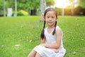 Portrait of beautiful little Asian child girl with two ponytail hair lying on green grass lawn Royalty Free Stock Photo