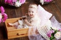 Portrait of a beautiful little baby girl with pink flowers. Sweet smiling girl sitting in wooden box on the floor Royalty Free Stock Photo
