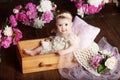 Portrait of a beautiful little baby girl with pink flowers. Sweet smiling girl sitting in wooden box on the floor Royalty Free Stock Photo