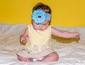 Portrait of a beautiful little baby girl in a yellow dress with a bow on her head that plays beads jewelry around his neck Royalty Free Stock Photo