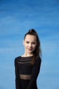 Portrait of a beautiful little brown-haired girl smiling on a blue background. Dressed in a black sweater Royalty Free Stock Photo