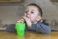 Pretty boy drinks iced tea through a plastic straw in the kitchen Royalty Free Stock Photo