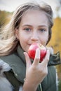 Portrait of beautiful little girl on autumn picnic. Little girl hold fruit in on background gold forest. Toddler eating