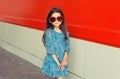 Beautiful little girl child in red heart shaped sunglasses and blue dress on city street Royalty Free Stock Photo