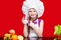 Portrait of beautiful little girl in form of cook isolated on red drink water