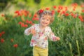 Portrait of a beautiful little girl having fun in field of red poppy flowers in spring. Royalty Free Stock Photo