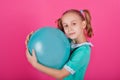 Portrait of a beautiful little girl hugging a blue balloon isolated on a pink background Royalty Free Stock Photo