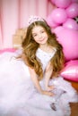 A portrait of a beautiful little girl in a studio decorated many color balloons