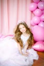 A portrait of a beautiful little girl in a studio decorated many color balloons