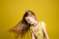Portrait of beautiful little girl with long hair smiling posing isolated at yellow studio background Royalty Free Stock Photo