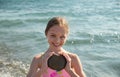 Portrait of beautiful little girl is playing with heart shape stone in sea waves. Kid and vacation, tourist destination Royalty Free Stock Photo