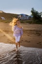 Portrait of beautiful little girl is playing in sea waves in sunset light Royalty Free Stock Photo