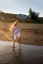 Portrait of beautiful little girl is playing in sea waves in sunset light. Kid and vacation, tourist destination Royalty Free Stock Photo