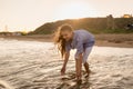 Portrait of beautiful little girl is playing in sea waves in sunset light. Kid and vacation, tourist destination Royalty Free Stock Photo