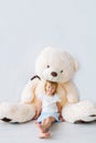 Portrait of the beautiful little girl sitting with a huge teddy bear. Royalty Free Stock Photo