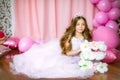 A portrait of a beautiful little girl in a studio decorated many color balloons