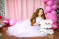 A portrait of a beautiful little girl in a studio decorated many color balloons