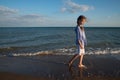 Portrait of beautiful little girl walking in sea waves in sunset light. Kid and vacation, tourist destination Royalty Free Stock Photo