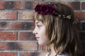 portrait of a beautiful little girl wearing a red wreath roses on her head. Brick background. Lifestyle Royalty Free Stock Photo