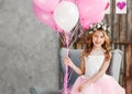 Portrait a beautiful little girl in a wreath of fresh flowers and an elegant pink dress celebrates her birthday in a white studio Royalty Free Stock Photo