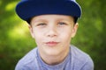 Portrait of beautiful little white boy in cap in green summer park on sunny day. Royalty Free Stock Photo