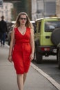 Portrait of beautiful long haired blonde plump woman in red close fitting sleeveless dress. Outdoors on cars background Royalty Free Stock Photo