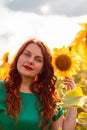 Portrait of beautiful long-haired curly-haired girl in a green dress in a field of sunflowers, vertical photo Royalty Free Stock Photo