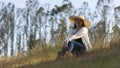 Portrait of beautiful long-haired hispanic young woman with a hat very cheerful sitting in a field against a background of