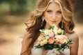 Portrait of beautiful luxury bride with roses wedding bouquet outdoors. Young woman with professional make up and hair style.