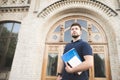 Portrait of a beautiful man with a beard holding books in his hands against the background of an old building Royalty Free Stock Photo