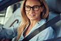 Portrait of a beautiful mature business woman driving a car, sitting behind steering wheel, looking at camera and Royalty Free Stock Photo