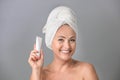 Portrait of beautiful mature woman with perfect skin holding tube of cream