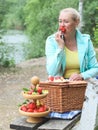 Portrait of a beautiful middle-aged caucasian blonde woman eating a big red and ripe strawberry Royalty Free Stock Photo