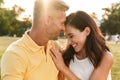 Portrait of beautiful middle-aged couple laughing and hugging while sitting on grass in summer park Royalty Free Stock Photo